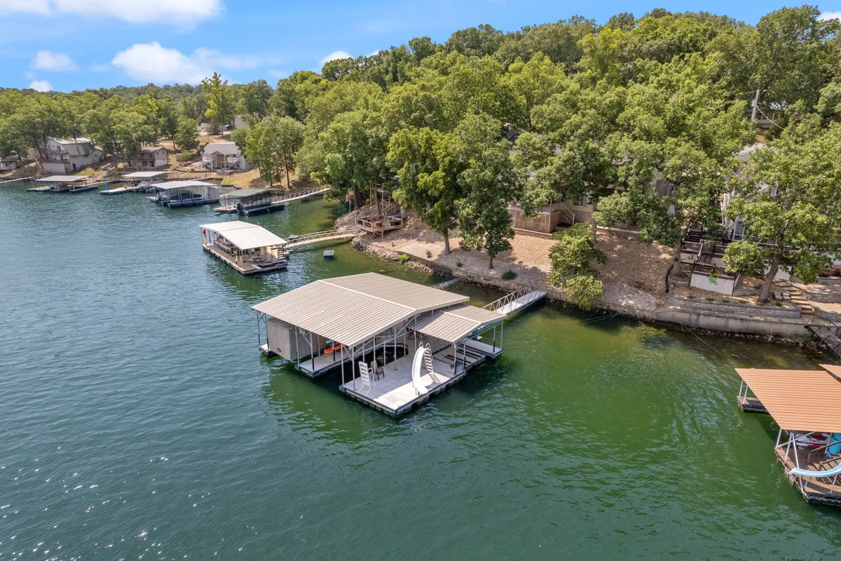 A serene lakeside scene with the dock, boats, and a peaceful tree line, highlighting direct access to the lake and outdoor activities. The water and natural surroundings evoke relaxation and local exploration.