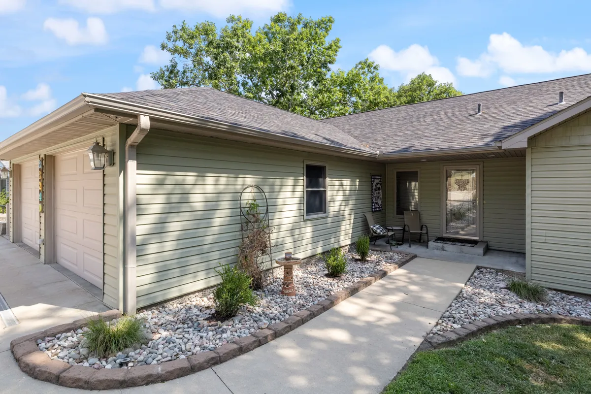 A wide view of the home's pathway leading up to the entrance, framed by decorative stone features and lush greenery. The inviting exterior suggests effortless arrivals and pleasant first impressions for guests.